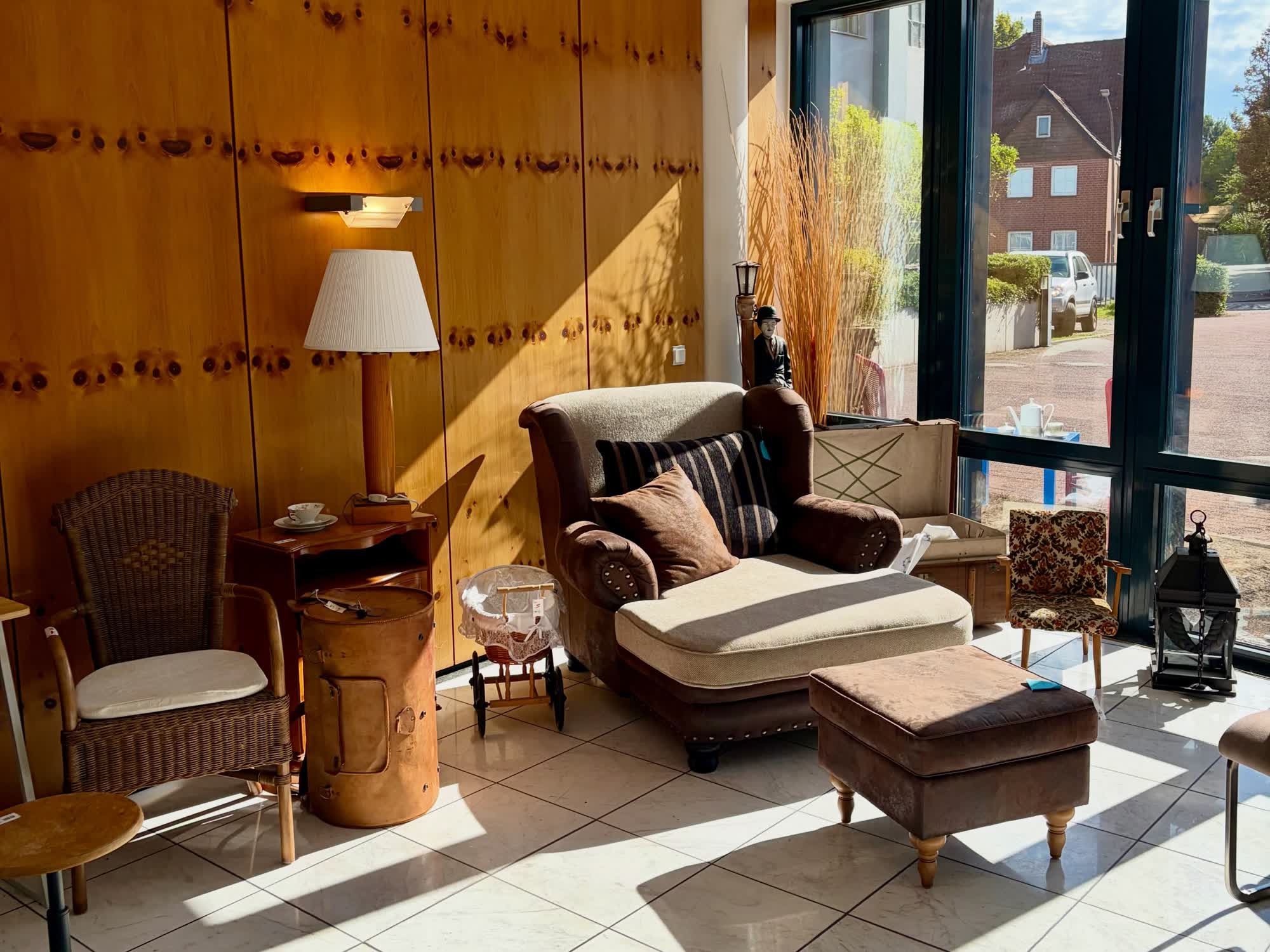 Ledersessel mit Hocker vor einer Holzwand, Sonnenlicht fällt durch die Fenster